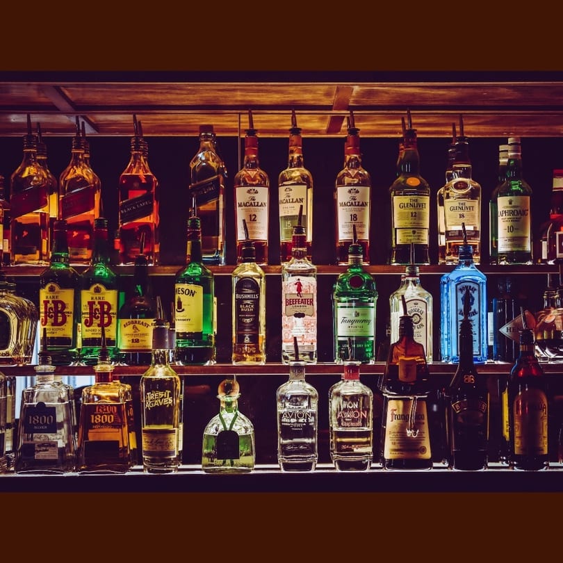 A well-stocked bar shelf displays numerous bottles of various spirits and liquors.